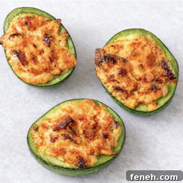 three baked avocado halves, stuffed with bacon and cheese filling.