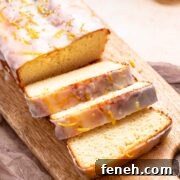 A keto iced lemon loaf that is sliced on a cutting board.