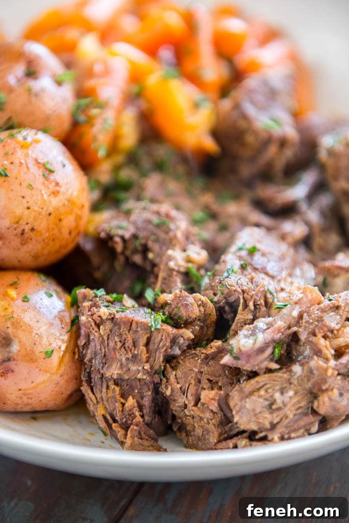 Pressure Cooker Pot Roast up close with carrots and potatoes on the side