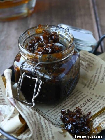 Bourbon and bacon jam in a clear glass jar on a tray lined with brown parchment paper.