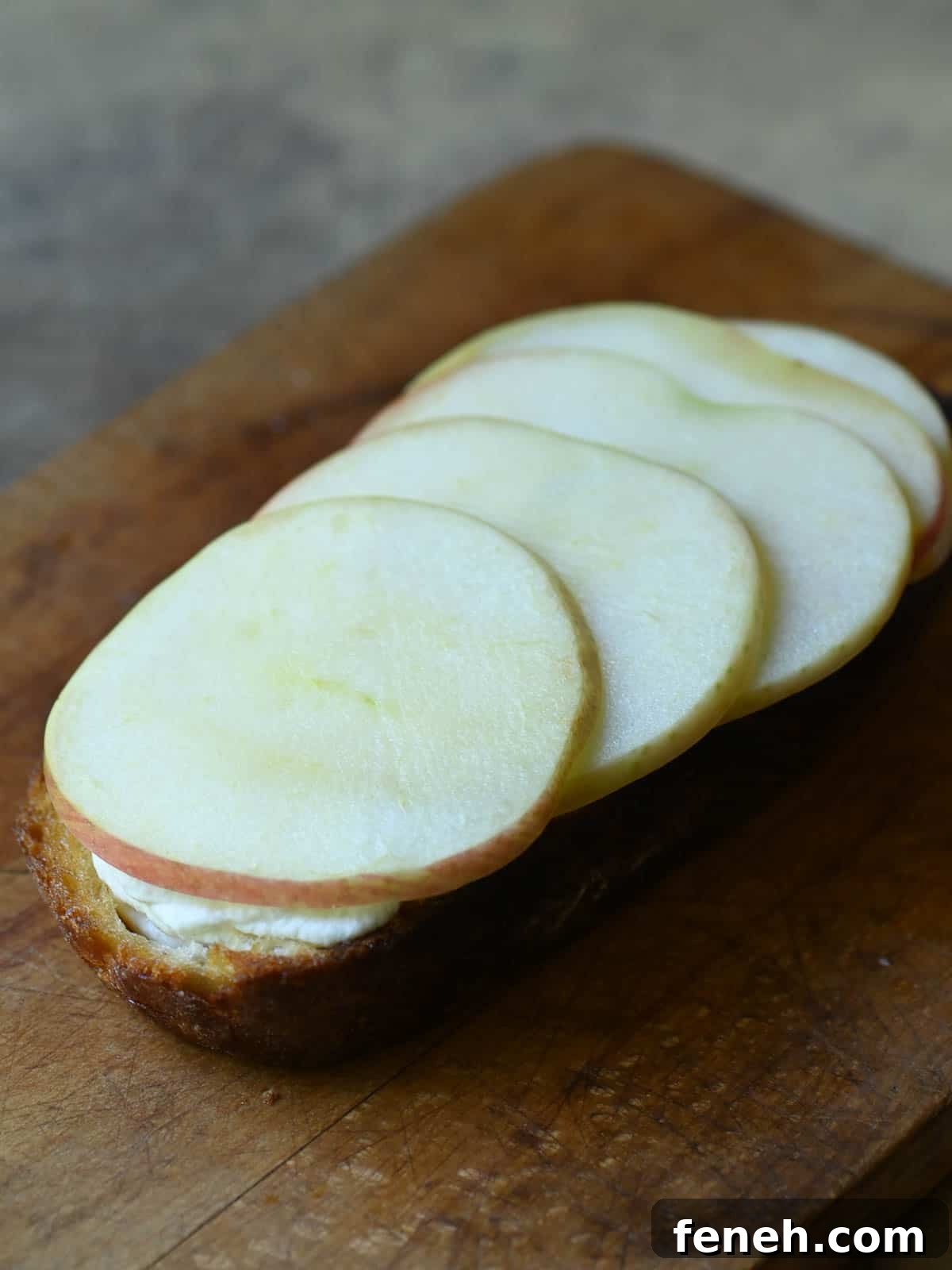Apples and ricotta on toast in a cutting board.
