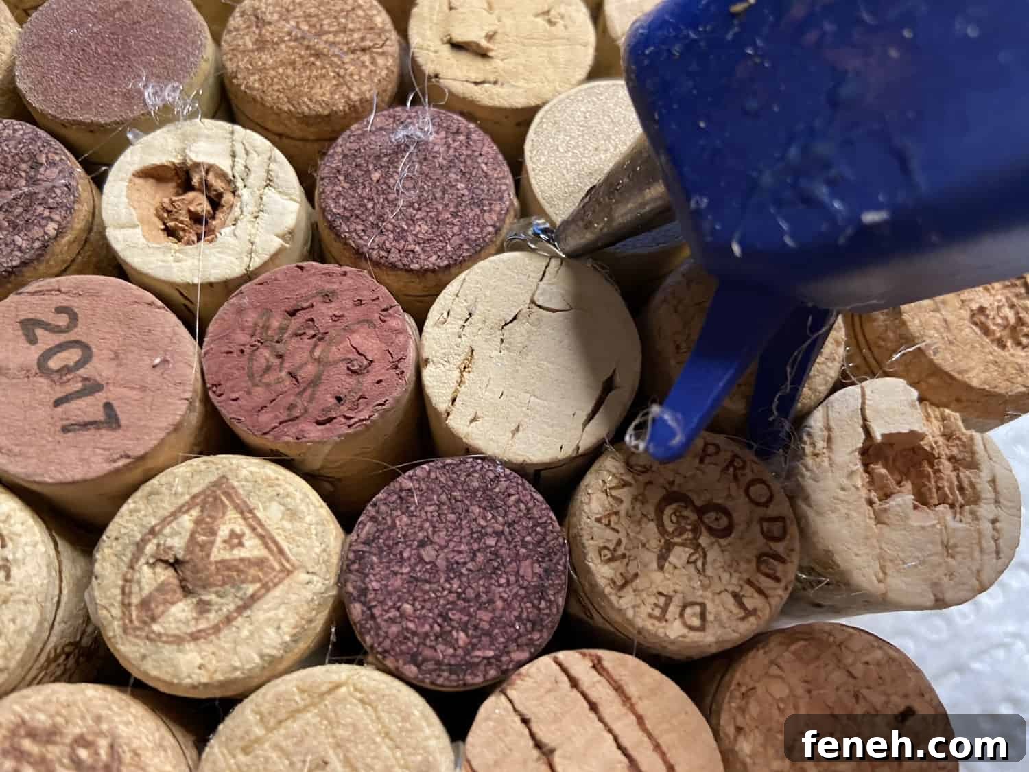 Using hot glue gun to place glue between the corks.