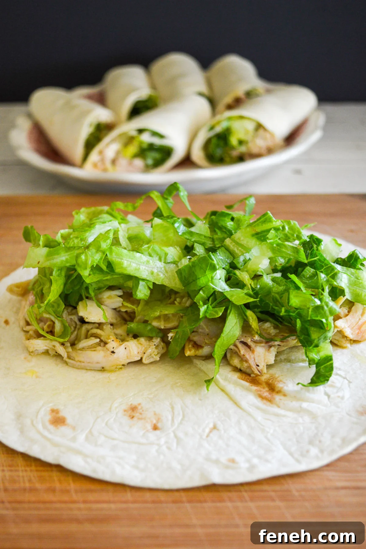 caesar chicken salad topped with lettuce on an open tortilla