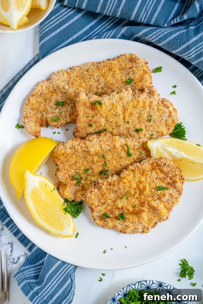 Overhead view of close up of air fryer pork schnitzel showing off golden brown breading and garnished with fresh parsley.