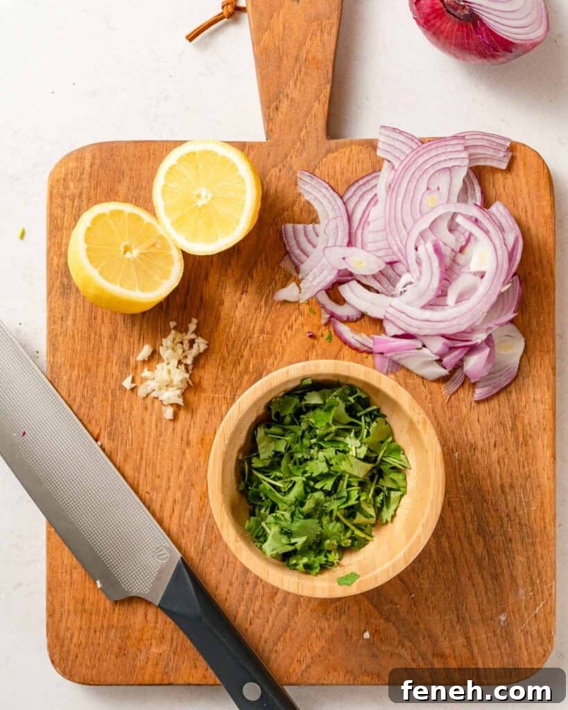 cut cilantro in bowl on cutting board with lemon garlic and sliced onion on the side.
