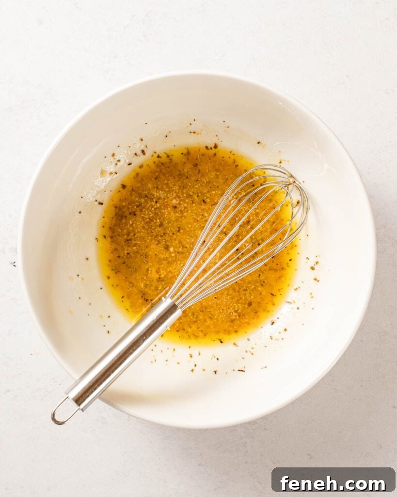 dressing in white bowl with whisk.