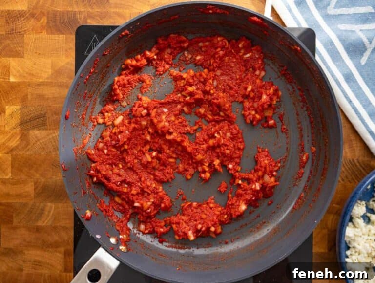 Step 2 Onions garlic and tomato paste sautéing in skillet for flavorful base.
