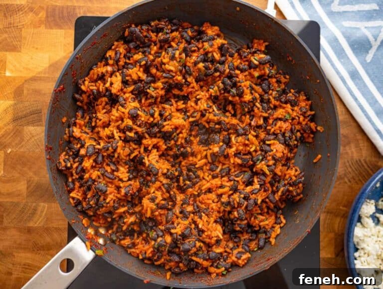 Step 3 Black beans and rice cooking together in skillet until coated in spiced tomato sauce.