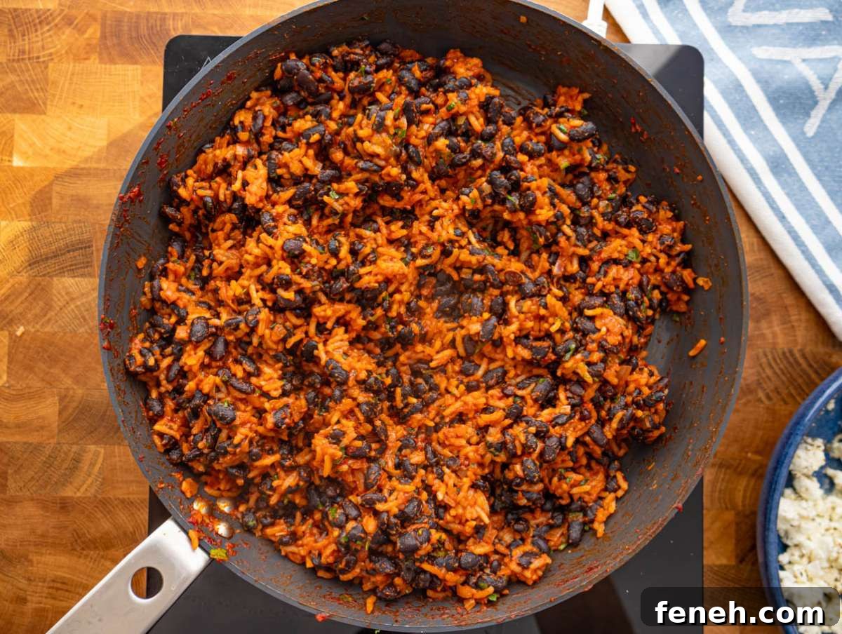 Step 3 Black beans and rice cooking together in skillet until coated in spiced tomato sauce.