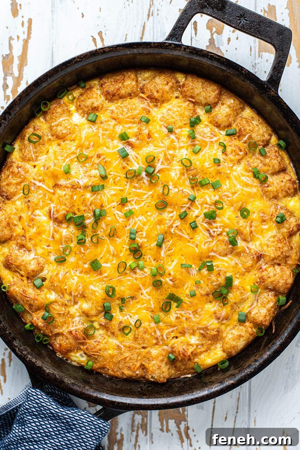 Golden brown cheesy tater tot breakfast casserole in a cast iron skillet.