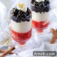 The final picture showing the finished blueberry cheesecake parfaits in clear glass mugs garnished with fresh whipped cream and crumbled graham crackers.