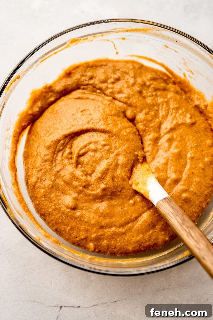 Pumpkin cake batter in a bowl being stirred with a spatula.