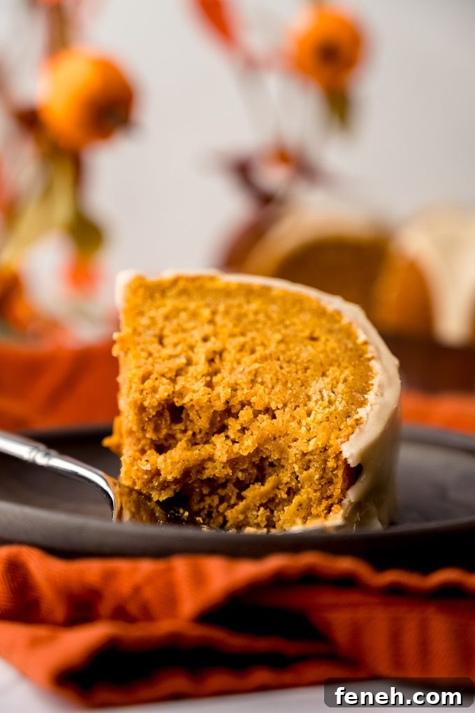 A slice of pumpkin Bundt cake on a plate with a fork and a bite taken out of it.