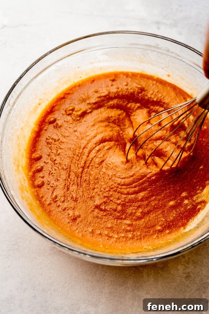 The wet ingredients for pumpkin cake in a bowl with a whisk.