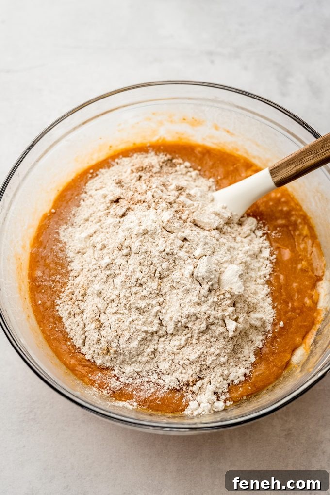 Pumpkin cake batter in a bowl being stirred with a spatula.