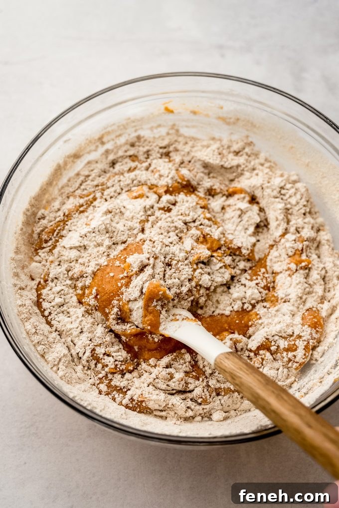 Pumpkin cake batter in a bowl being stirred with a spatula.