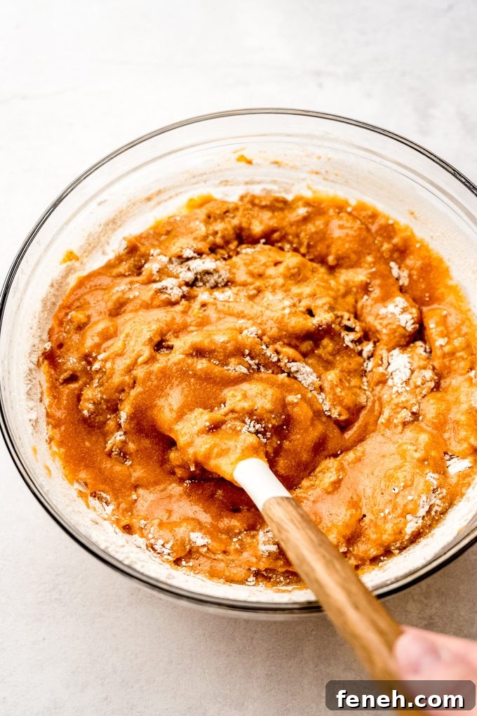 Pumpkin cake batter in a bowl being stirred with a spatula.