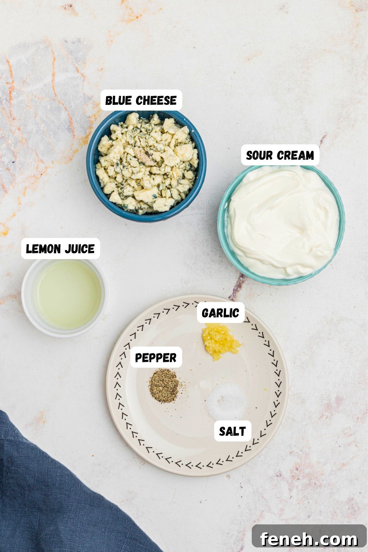 Sour cream, blue cheese, lemon juice, and seasonings, in small bowls and labeled on a marble table. 