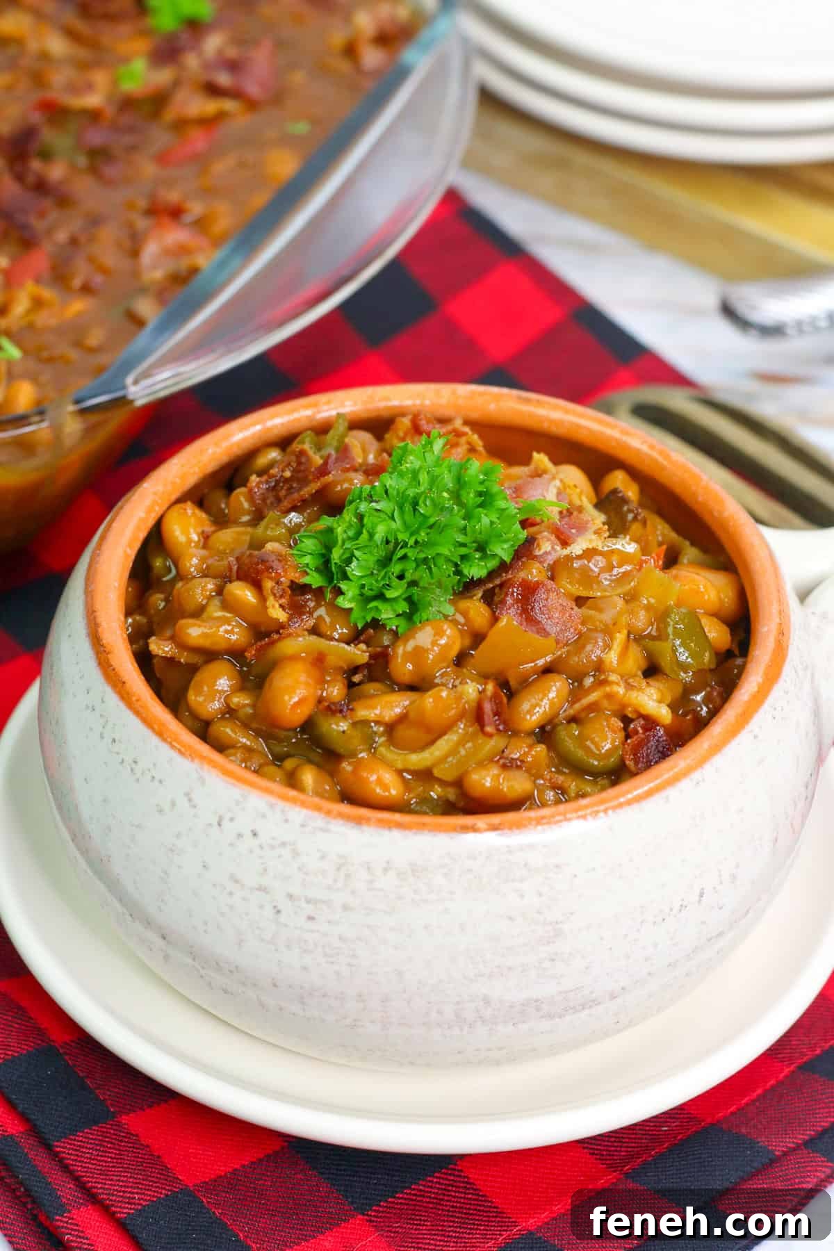 a bowl of cowboy bbq baked beans with onion, bell pepper, and bacon garnished with parsley.