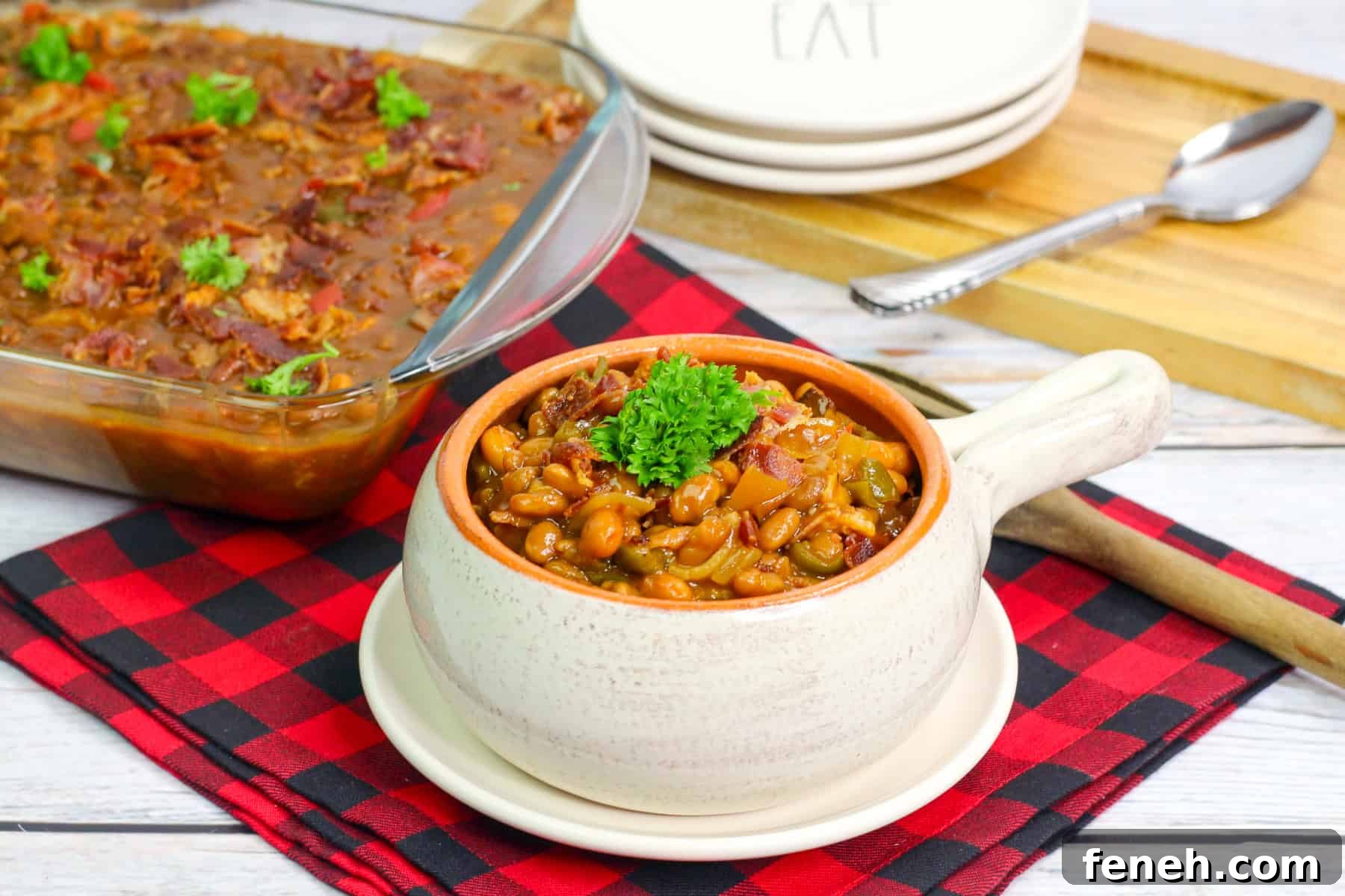 a bowl of bbq baked beans with a 9x13 pan of beans in the background.