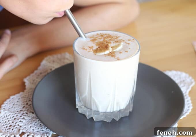 Sipping oat smoothie set on a dark plate.