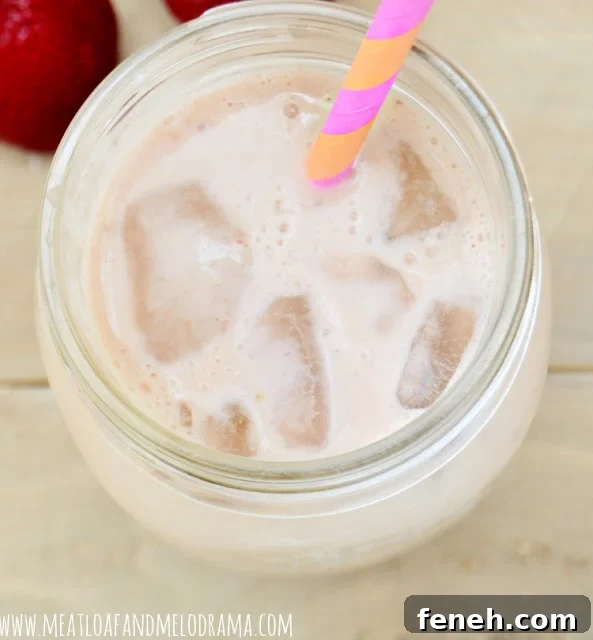 fruity breakfast smoothie in a mason jar with ice and straw