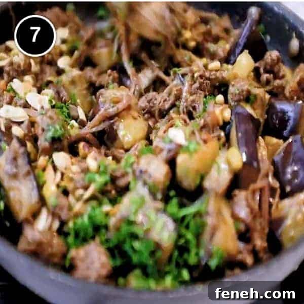 Creating spiced eggplant and lamb in a small frying pan.