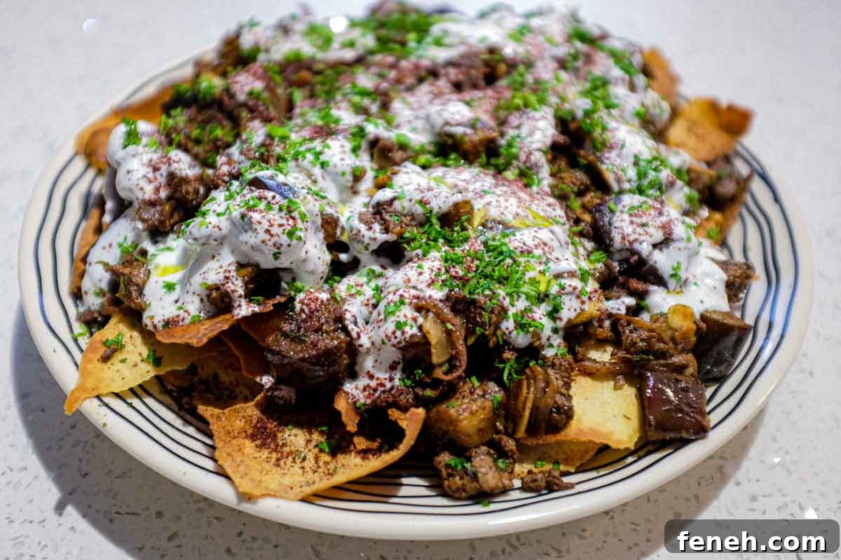 a platter of Lamb & Eggplant Fatteh garnished with fresh parsley and sumac