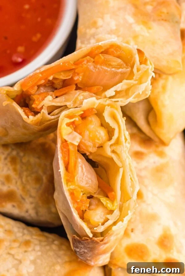 Golden crispy egg rolls on a plate with dipping sauce