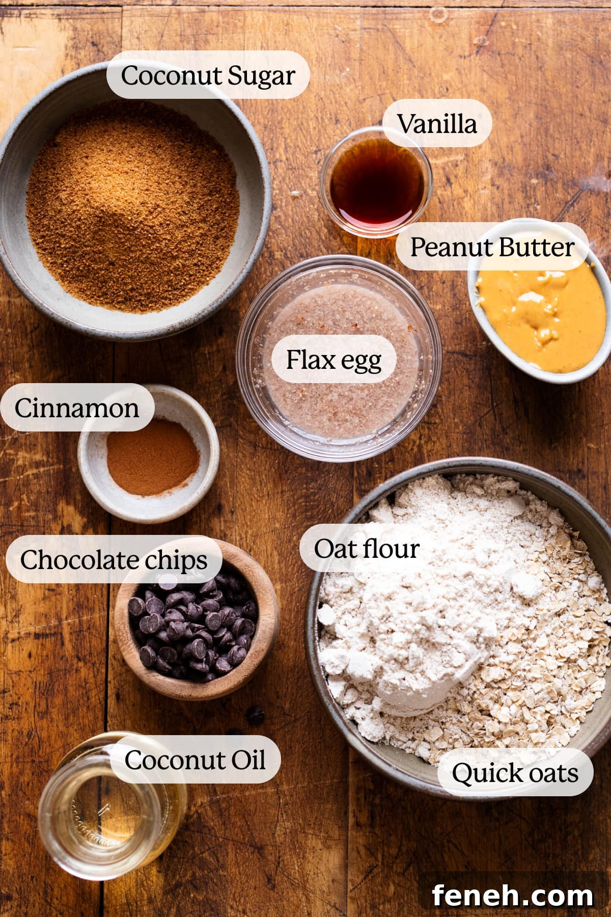 Ingredients for vegan oatmeal chocolate chip cookies arranged on a wooden board with the names of the ingredients displayed on the image.