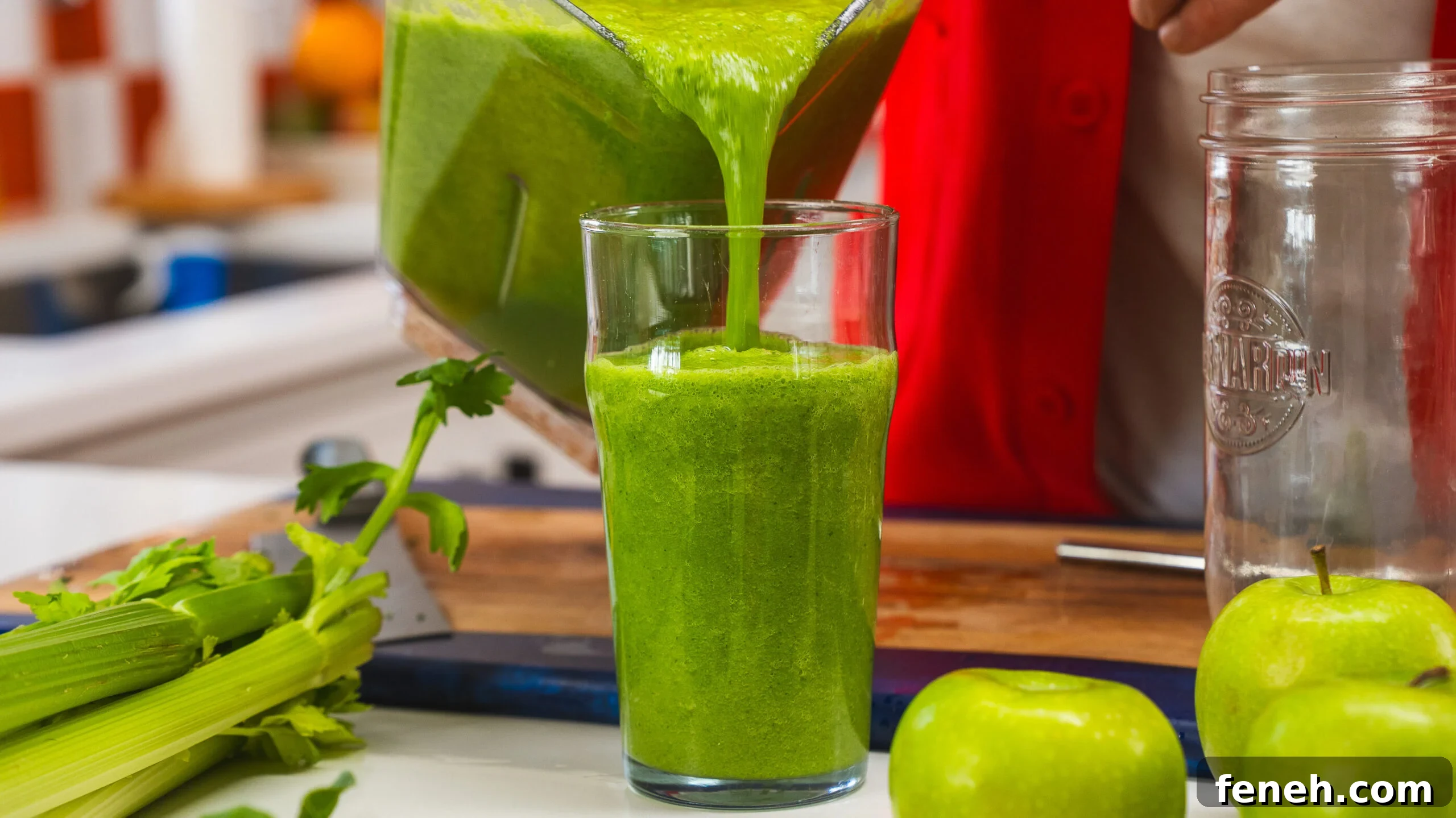 Green juice being poured into a glass from a blender.