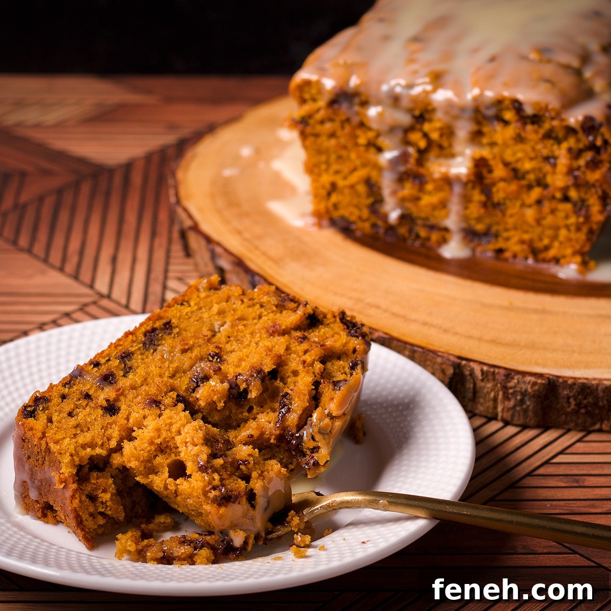 A slice of pumpkin chocolate chip bread on a white plate with a bite resting on a gold fork.