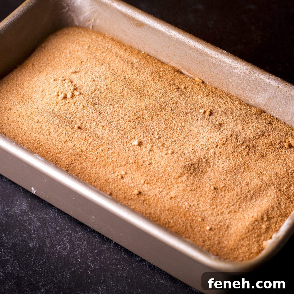A loaf pan that contains layers of cake batter and cinnamon sugar.