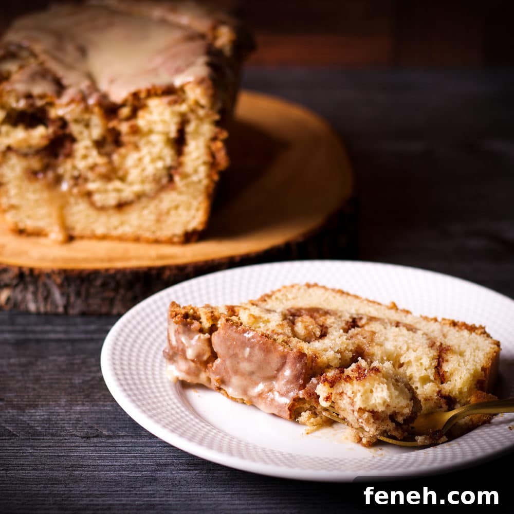 A slice of cinnamon swirl loaf cake on a white plate, ready to eat.