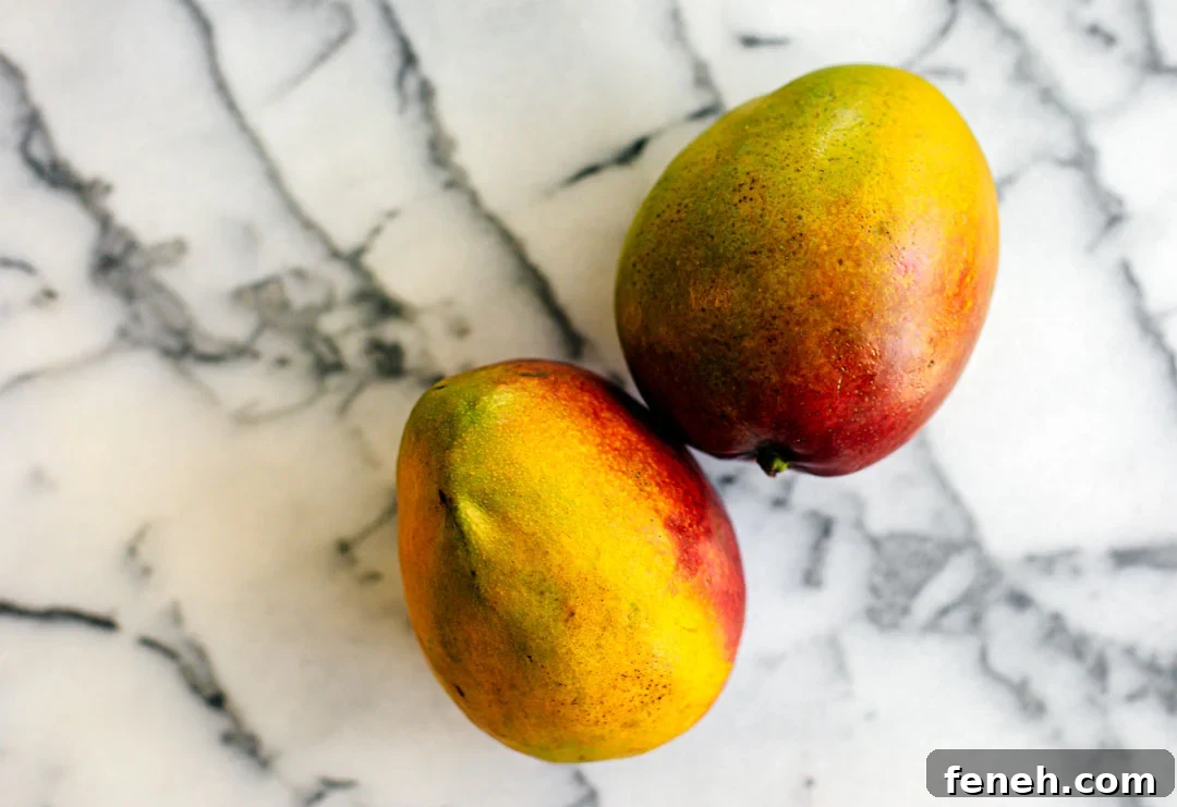 A couple of mangoes on a marble slab.