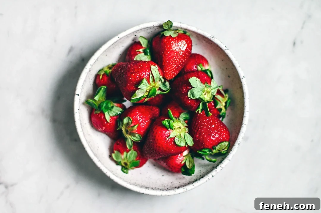 White bowl filled with juicy red strawberries.
