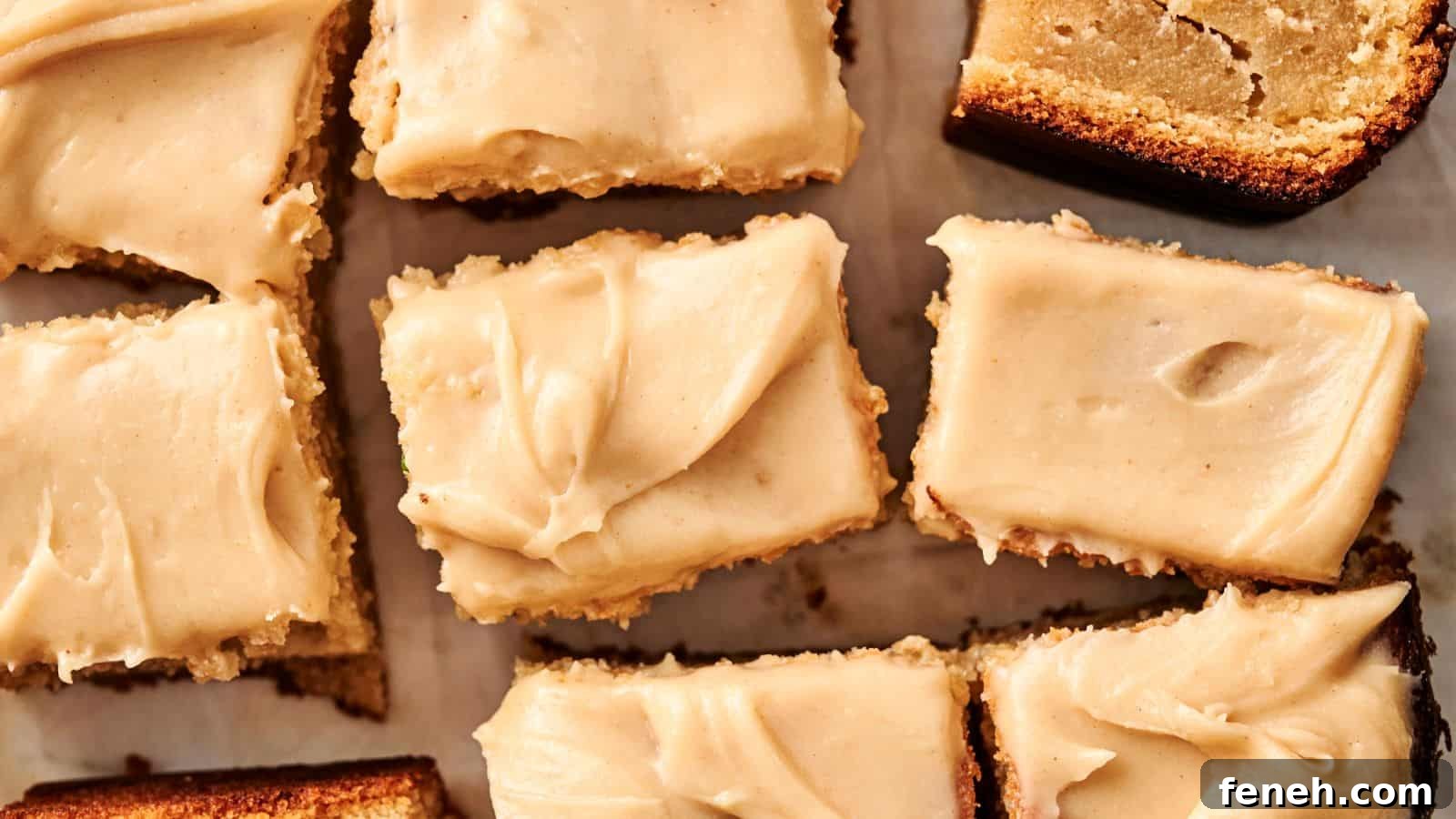 Close-up of frosted square cake pieces with a light brown crust on parchment paper.