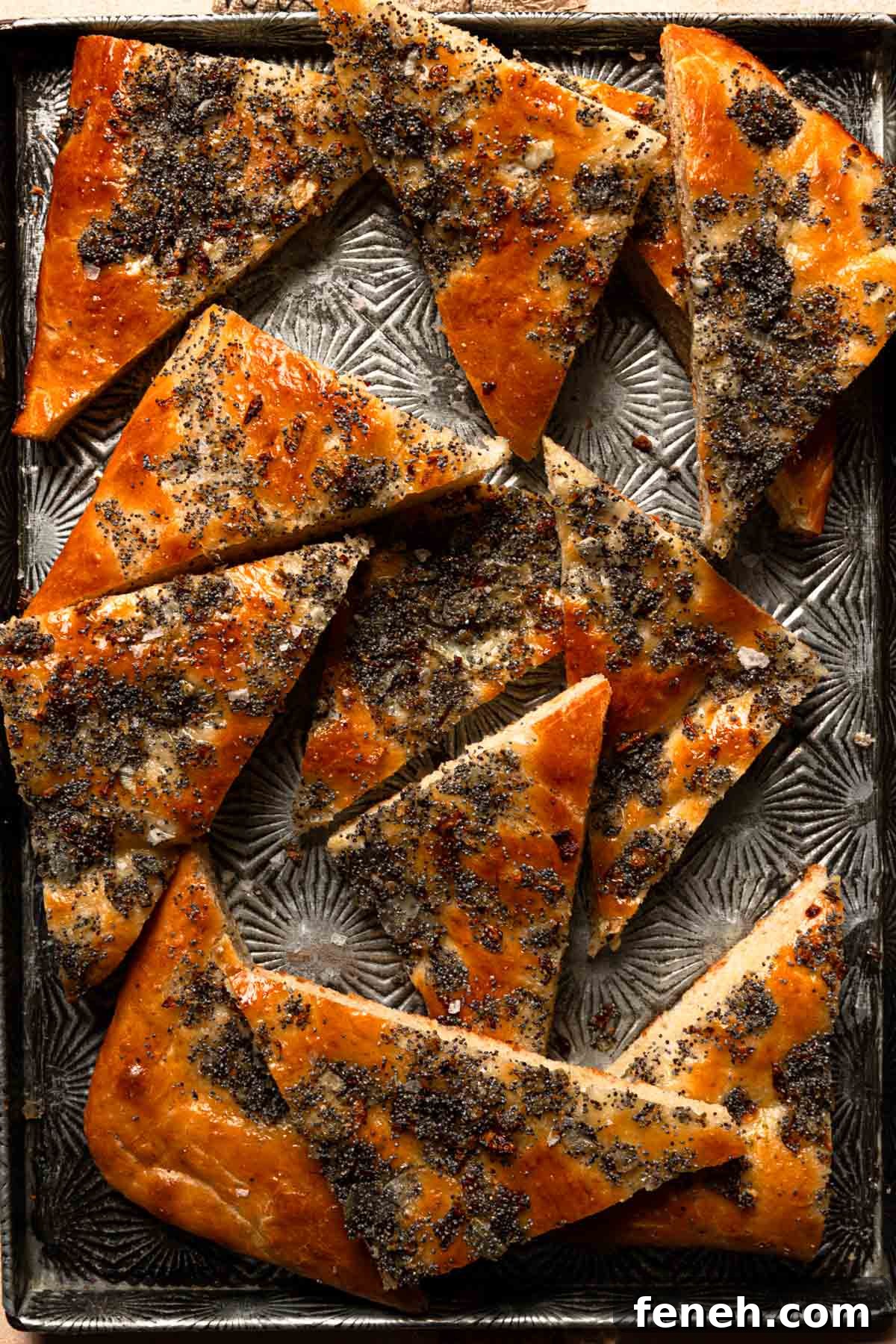 sliced Pletzel topped with onion and poppy seed on a tray.