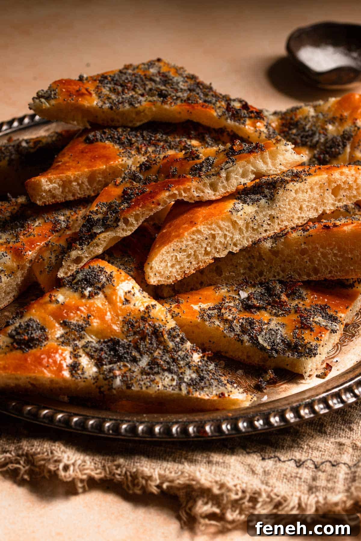 Sliced jewish focaccia topped with onions and poppy seeds.