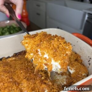 Serving spatula lifting a portion of Cheez-It Chicken from a baking dish.