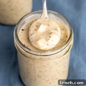 closeup image of spoon in tan gluten free cream of chicken soup with herb flecks in mason jar on blue cloth