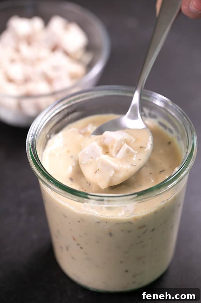 Fingers holding spoon with closeup on spoonful of cream of chicken soup