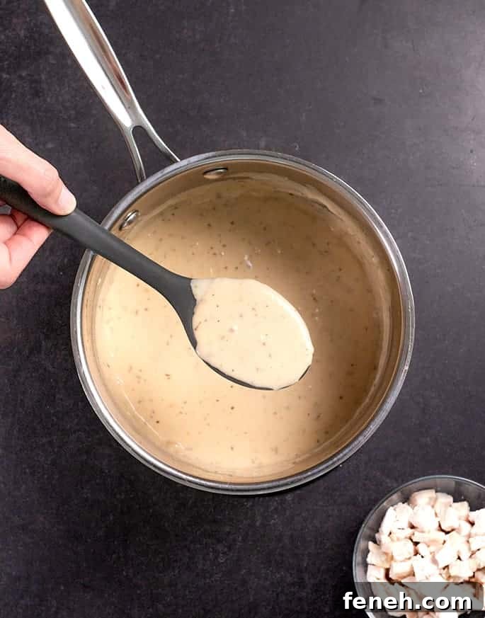 Overhead image of spoonful of cream of chicken soup in black spoon over pan