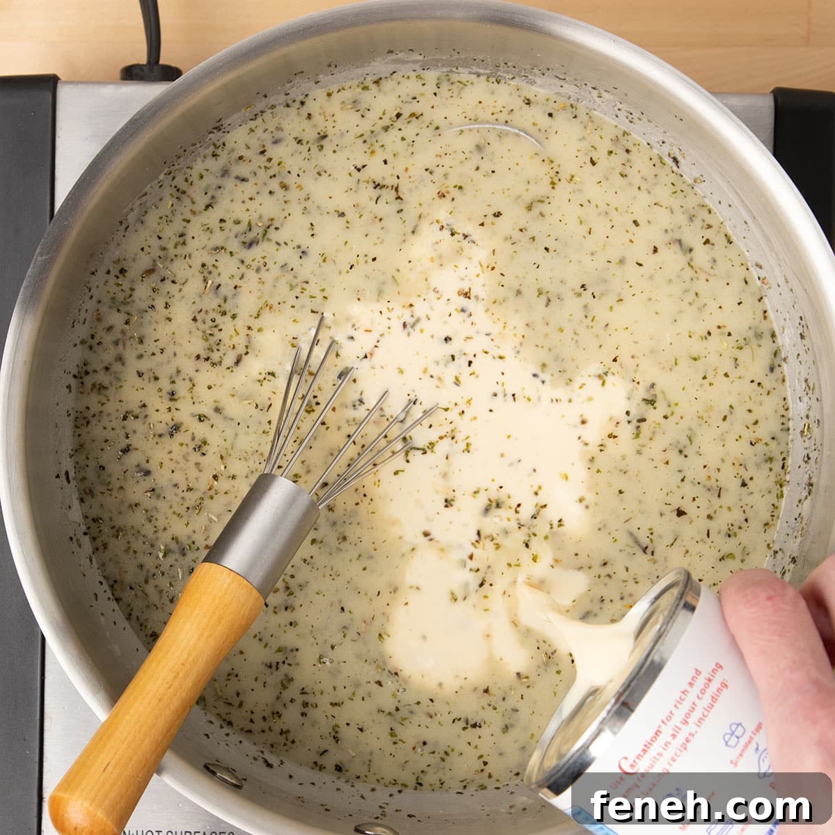 pouring evaporated milk from can into same saucepan with whisk in pan