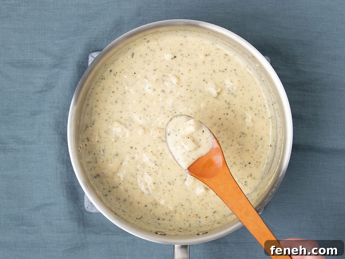 brown mixing spoon with cream of chicken soup over same metal pan on blue cloth