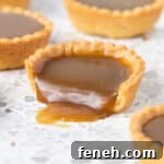 Close up on a tart bite a bite taken off and butterscotch sauce pouring out.