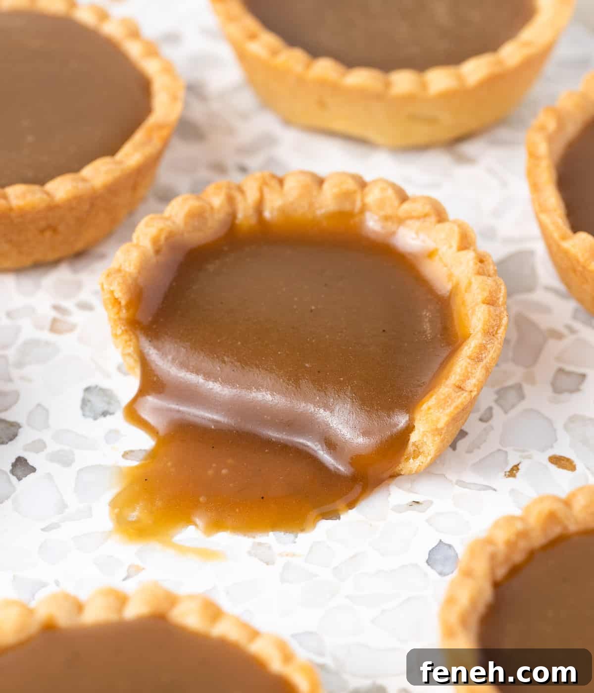 Butterscotch sauce oozing out of a tart cut in half.