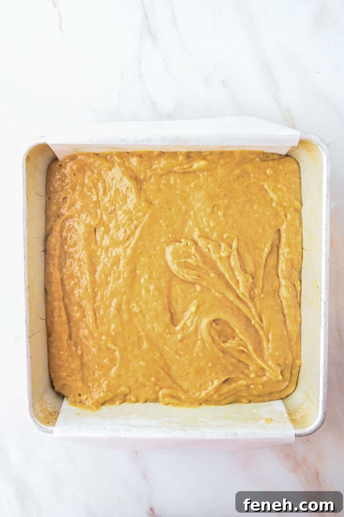 Banana Blondies batter in a parchment paper lined square baking pan.