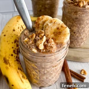 banana bread overnight oats in a mason jar with a spoon in it for serving. Topped with sliced bananas and walnuts