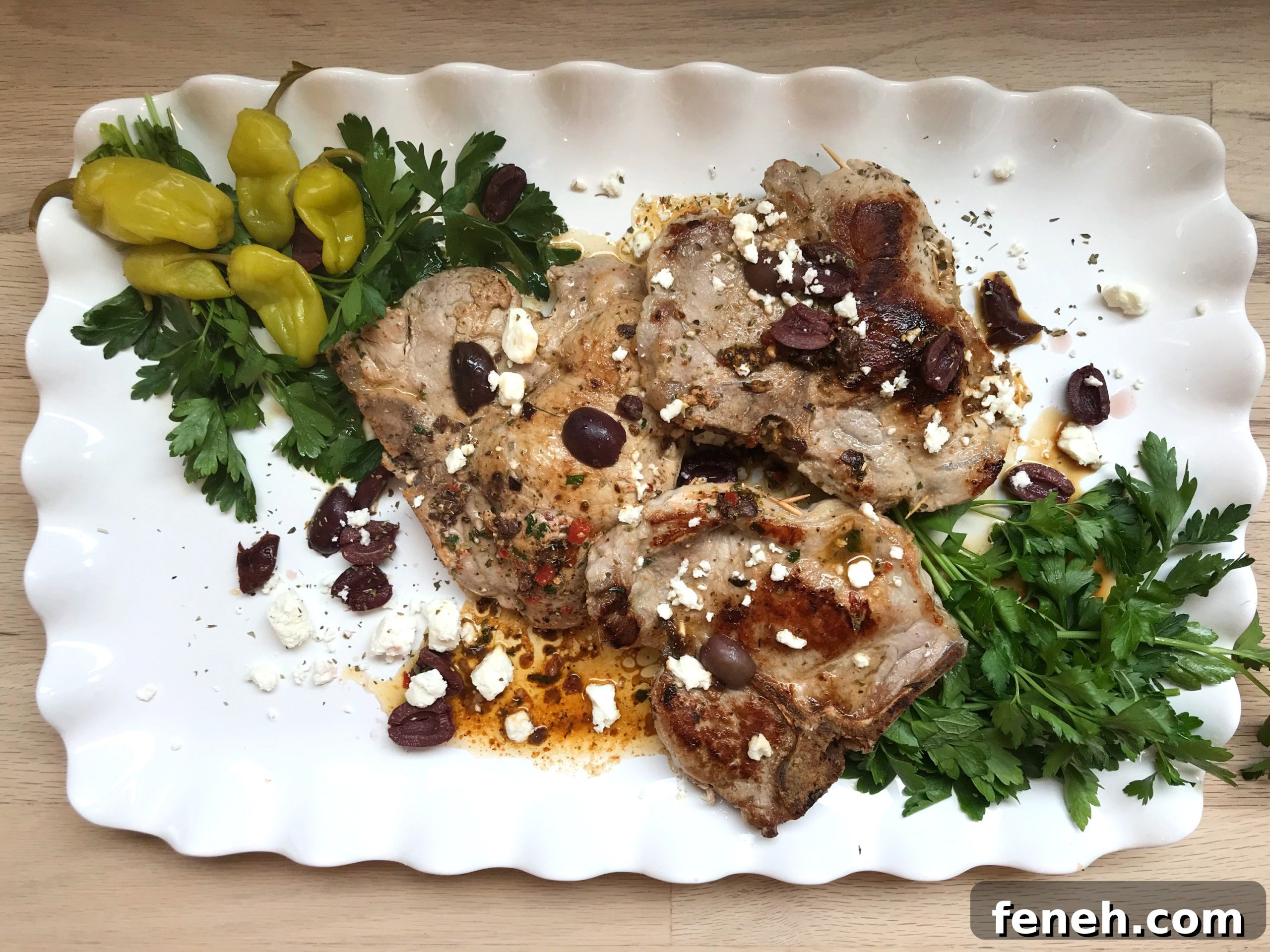 White, fluted plate of Mediterranean stuffed pork chops.